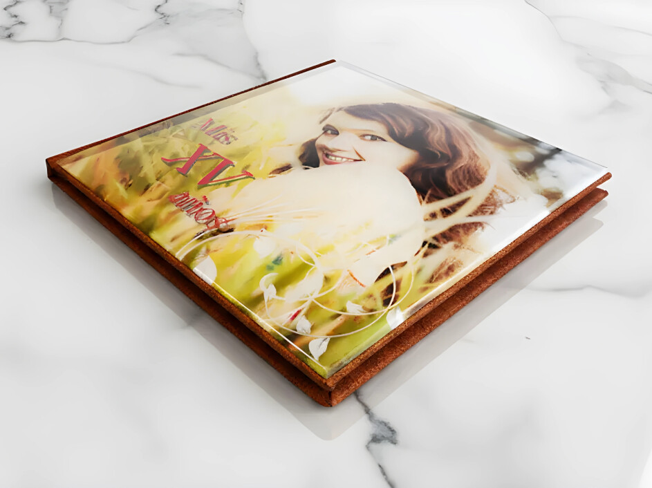 Fotobook de acrílico Mi Album con portada personalizada para XV años, impreso en papel metalizado y empastado en pro-piel color miel sobre fondo de mármol blanco.